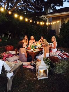 a group of women sitting around a table outside at night