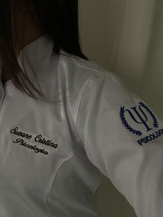 the back of a woman's white jacket with blue trims and embroidered logos