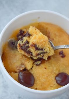 a close up of a spoon in a bowl of food with pudding and raisins