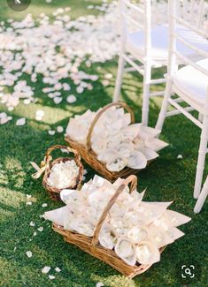 two baskets filled with flowers sitting on top of a grass covered field next to white chairs