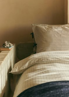 an unmade bed with two pillows on top of it next to a night stand