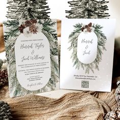 two wedding cards with pine cones and evergreens on them, sitting next to each other