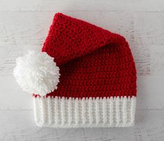 a red and white crocheted hat with a pom - pom on top