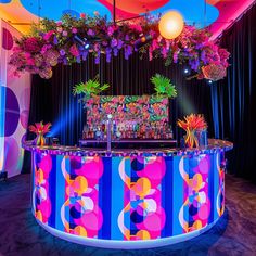 a brightly lit bar with hanging plants and flowers on the top, in front of a curtained backdrop