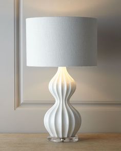 a white table lamp sitting on top of a wooden table