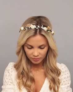 a woman wearing a flower crown on her head and looking down at her cell phone