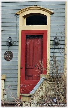 a red door sits in front of a blue house