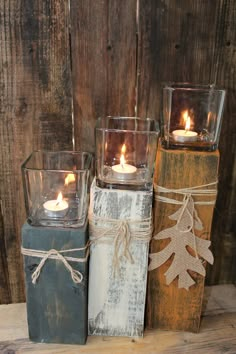 three candles are wrapped in burlap and tied with twine, sitting on top of wooden blocks