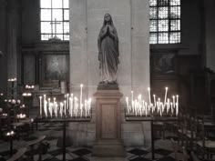 the interior of a church with candles lit up in front of it and a statue