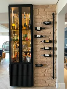 a wine rack with bottles and glasses on it in front of a brick wall that is filled with liquor