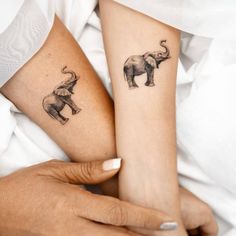 two people with matching tattoos on their arms holding each other's hands and one has an elephant tattoo on it