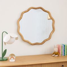 a mirror sitting on top of a wooden shelf next to a lamp and bookcase