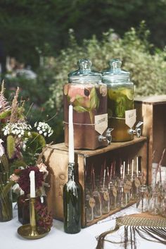 two jars filled with liquid sitting on top of a table next to flowers and candles