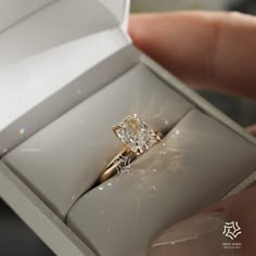 a person is holding an engagement ring in a box