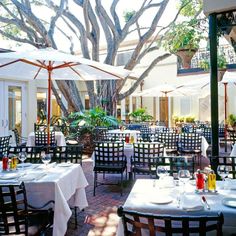 an outdoor dining area with tables, chairs and umbrellas set up for people to eat