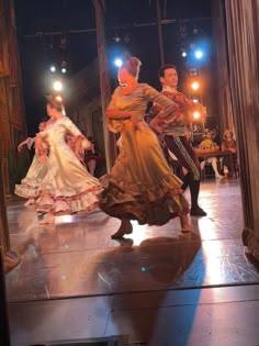 people are dancing on the stage in dresses and headdresses at an event