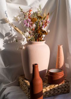 three vases with flowers in them are sitting on a wicker basket next to each other