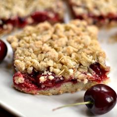 cherry crumbler bars on a white plate with cherries