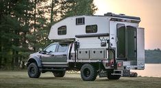 a truck with a camper attached to it parked in front of a body of water