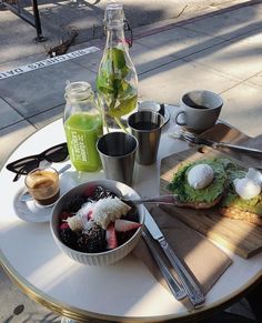 a table topped with food and drinks on top of a wooden table next to a sidewalk