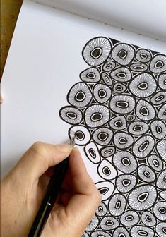 someone is drawing an intricate design with black and white ink on a piece of paper