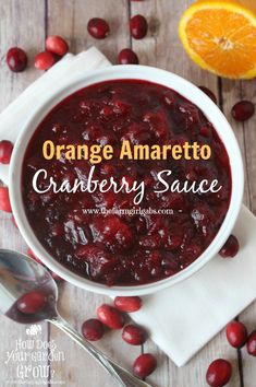 an orange and cranberry sauce in a white bowl with spoons next to it