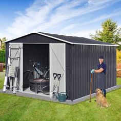 a man standing in front of a shed with his dog next to it and holding a mop