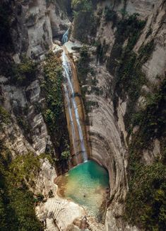 an aerial view of a waterfall in the middle of a mountain with a body of water