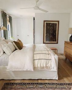 a large white bed sitting in a bedroom next to a wooden dresser