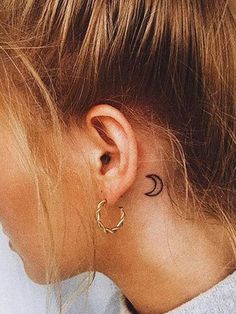 a black and white photo of a woman's ear with the moon tattoo on it