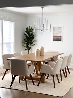 a dining room table with white chairs and a potted plant