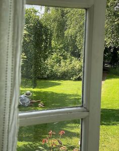 an open window with the view of a garden and trees from it's outside