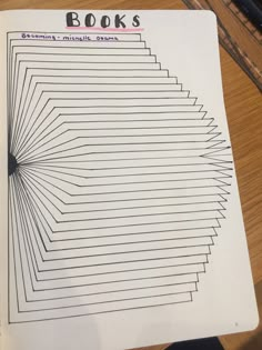 a book with lines drawn on it sitting on top of a wooden table next to a pen