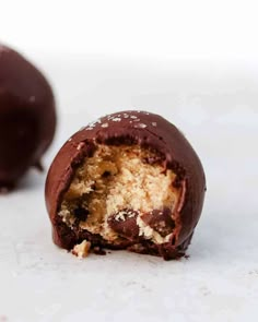 a half eaten chocolate ball on a white surface with one bite taken from the inside