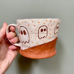 a hand holding a coffee cup with two ghost faces on it