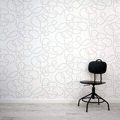 a black chair sitting in front of a wall with a white pattern on the wall