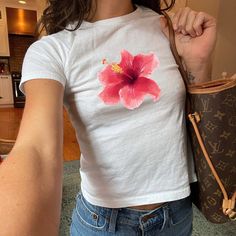 "Pink Hibiscus Flower" Graphic Slogan Printed On Aesthetic Retro Vintage 90s Y2k Baby Tee Shirt with our own unique font. (Model is wearing size XS for reference) 🎁 Our unisex baby tee is a perfect gift for her or him, offering universal comfort, style, and versatility for any occasion. 🧵 Features : ‣ 90s baby tee style (for adults) ‣ 100% cotton ‣ Double-needle stitched neckline ‣ Seamless collar ‣ Classic fit ‣ True to size (see size chart) ‣ Y2K vintage streetwear fashion Baby tees, popular in the '90s, have short sleeves and a slightly cropped body, giving a flattering feminine shape. They originated in the skater/raver scene and were part of the era's child-like fashion trend. 📏 Sizing : Fit's true to size. We recommend sizing down if you prefer a tighter fit. (please note these ar Baby Tees 90s, Baby Tee Shirt, Funny Baby Tees, Aesthetic Baby, Unique Font, Baby Tee Shirts, Pink Hibiscus, Aesthetic Retro, Streetwear Mode