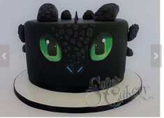 a black cake with green eyes and spikes on it's head is decorated like a cat