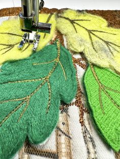 a close up of a piece of cloth with leaves on it and a sewing machine in the background