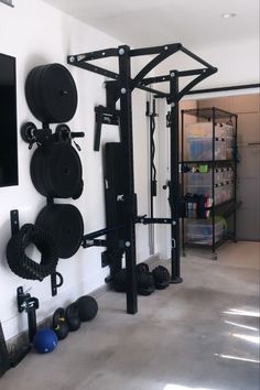 a home gym with several squat racks and weight plates on the wall next to it