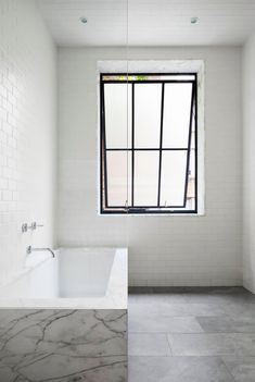 an empty bathroom with a large window in the corner and marble flooring on the walls