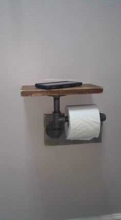 a toilet paper dispenser with a cell phone on the wall above it