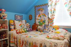 a child's bedroom with blue walls and rainbow decorations on the bed, bookshelf