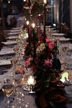 a long table is set with wine glasses and candles for an elegant dinner or party