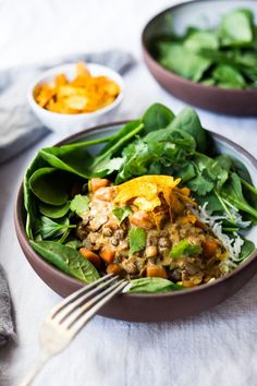 a salad with spinach, carrots and other toppings in two brown bowls