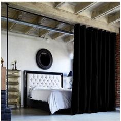 a bedroom with black curtains and a white bed in front of a mirror on the wall