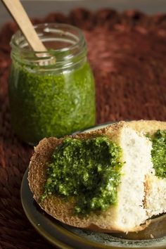 a sandwich with pesto on it sitting on a plate next to a jar of pesto