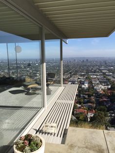 a wooden bench sitting on top of a cement floor next to a large glass window