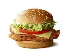 a chicken sandwich with lettuce, tomato and cheese on a sesame seed bun