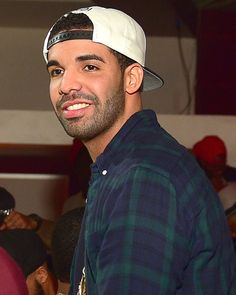 a man wearing a hat standing in front of a group of people at a party